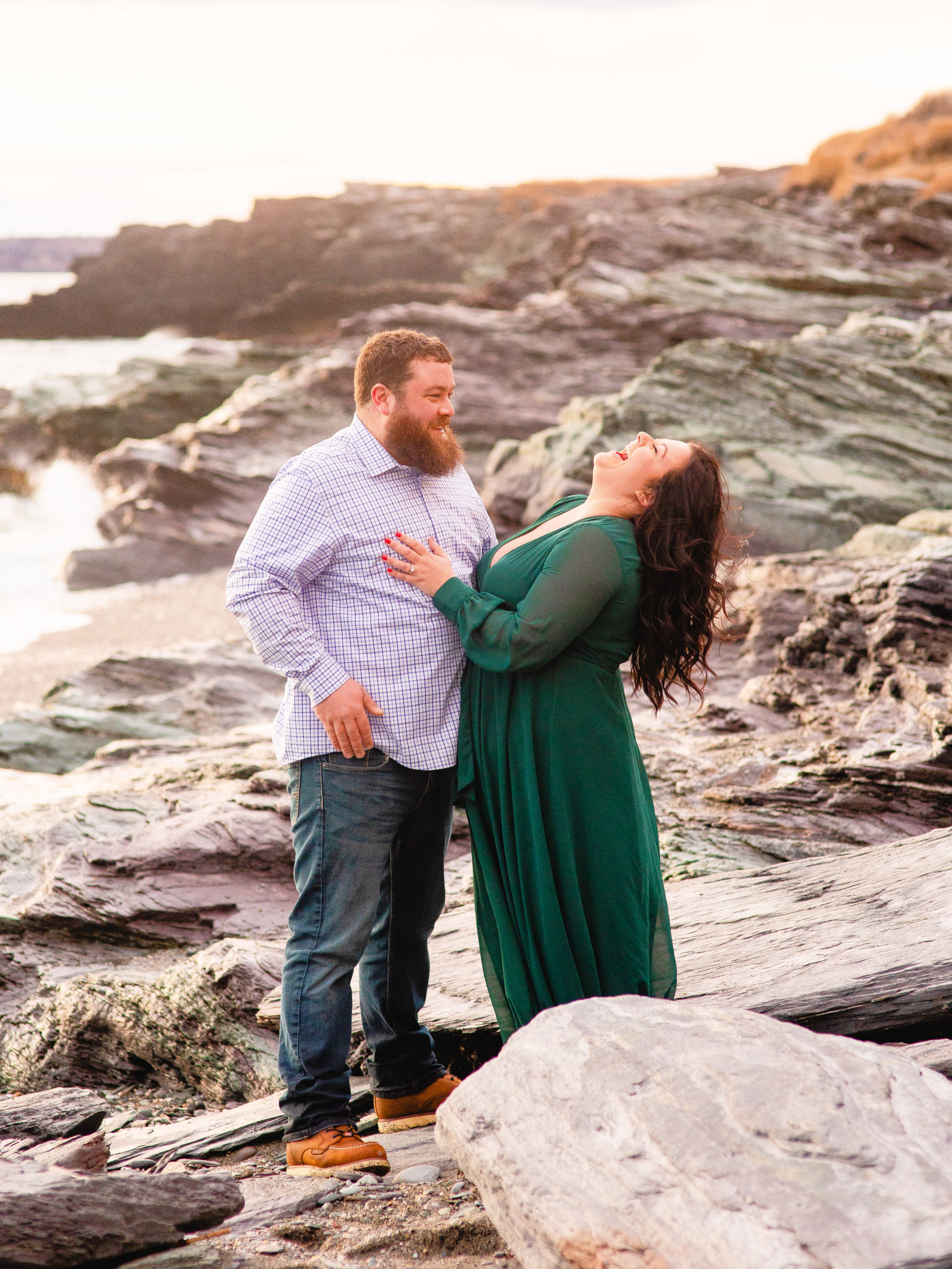 Engaged couple stands on the beach during their engagement session at Brenton Point State Park.