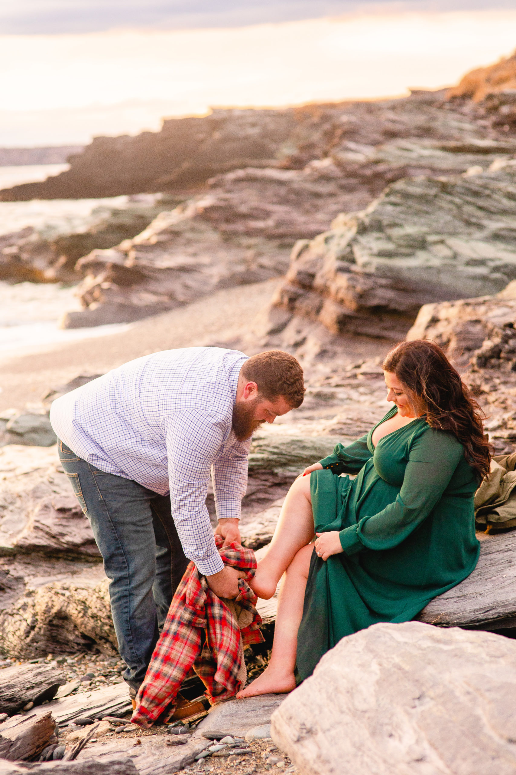 Groom wipes the sand off of bride's feet at Brenton Point State Park.
